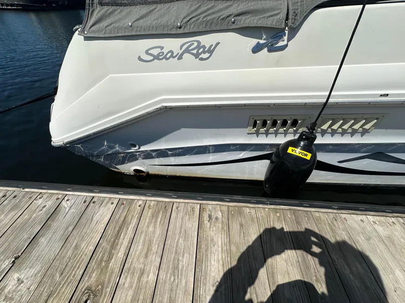 Slide: The Image of 1990 Sea Ray 310 Sundancer docked, showing rear view with logo and protective fender. - 9