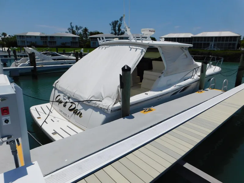 Slide: The Image of 2001 Tiara Yachts 3800 Open docked at marina, covered, with nearby boats and buildings. - 3