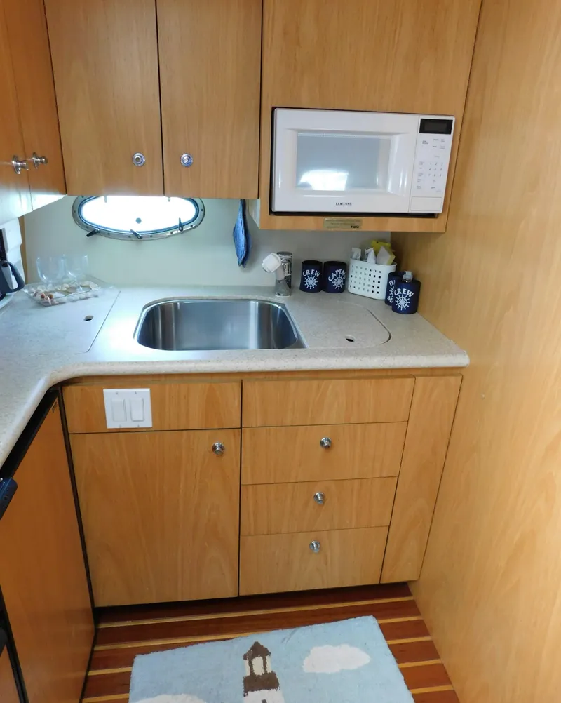 Slide: The Image of 2001 Tiara Yachts 3800 Open kitchen with sink, microwave, and wooden cabinetry. - 36