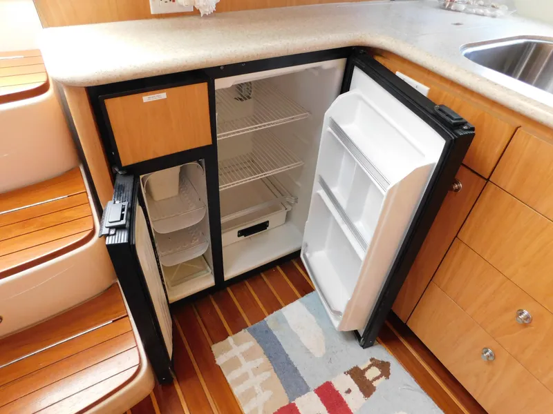 Slide: The Image of Open mini fridge in 2001 Tiara Yachts 3800 Open, wooden interior, compact kitchen space. - 37