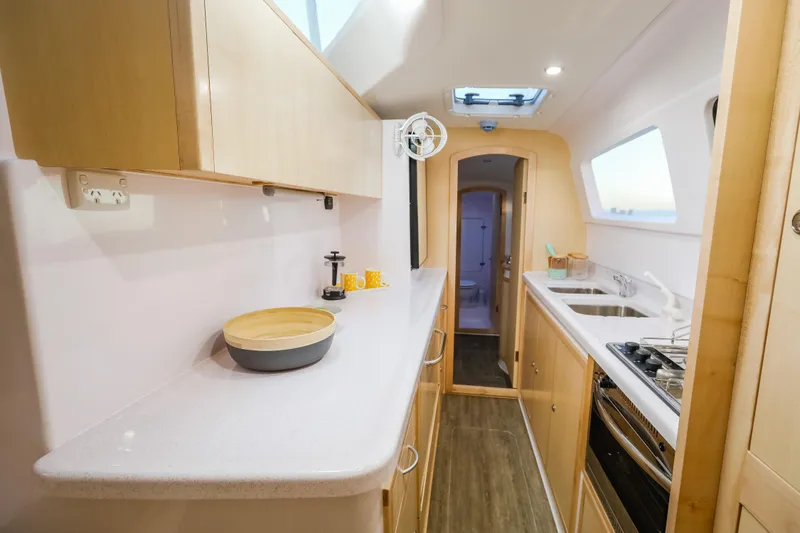 Slide: The Image of Modern Seawind 1260 yacht kitchen interior, featuring sleek countertops and wooden cabinetry, 2025 model. - 21