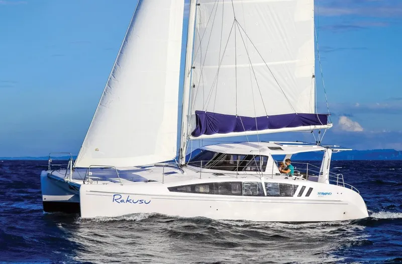 Slide: The Image of 2025 Seawind 1260 catamaran sailing on open water with white sails and blue accents. - 5