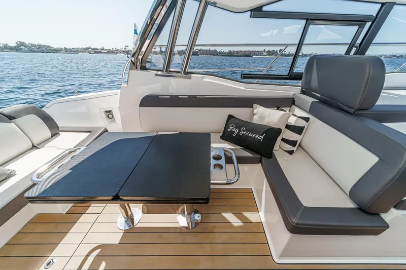 Slide: The Image of 2023 Bavaria SR36 yacht interior with sleek seating and table, overlooking serene waters. - 28