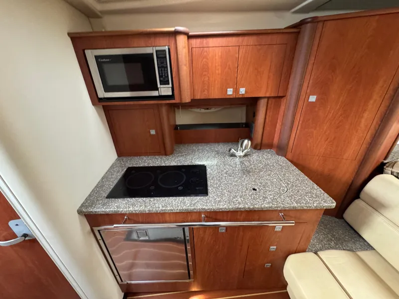 Slide: The Image of 2011 Monterey 320 Sport Yacht kitchen with microwave, stovetop, and wooden cabinetry. - 21