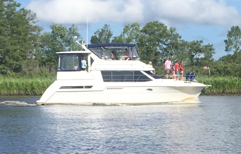 Slide: The Image of 1997 Carver 405 Aft Cabin Motoryacht cruising on a serene river with lush greenery. - 3