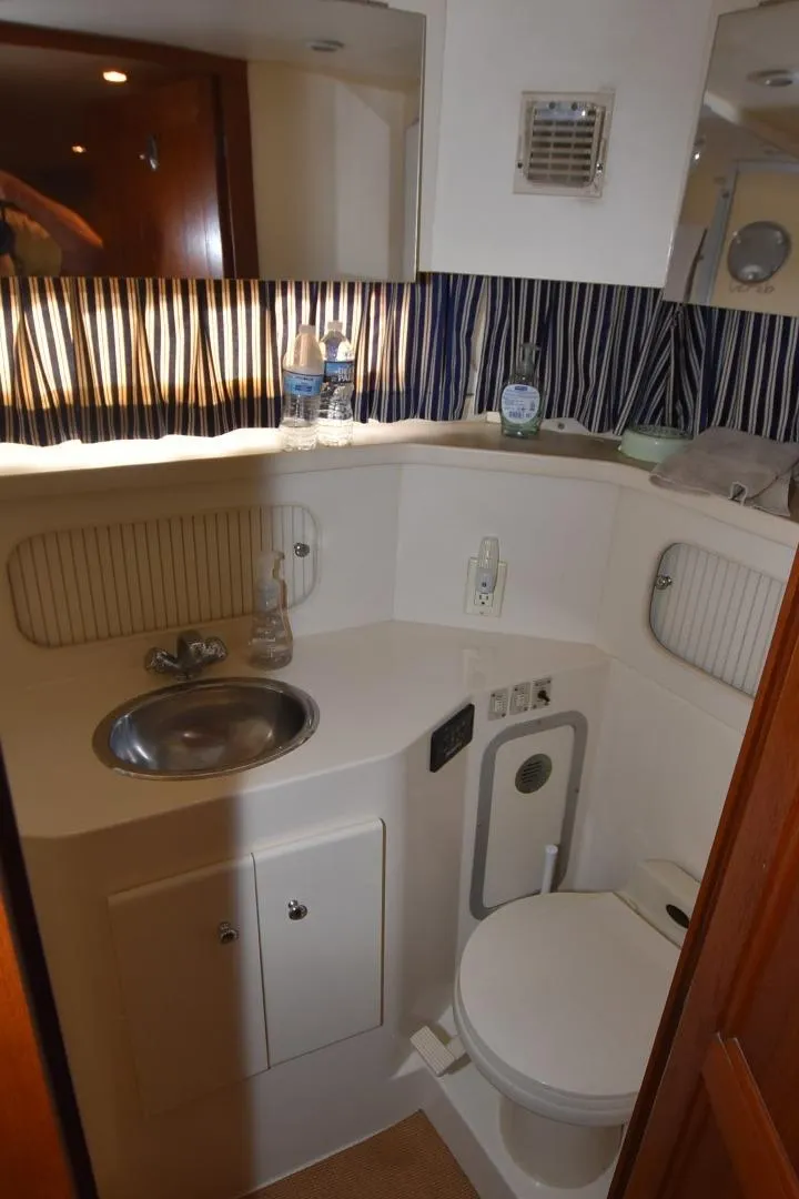 Slide: The Image of 1997 Carver 405 Aft Cabin Motoryacht bathroom with sink, toilet, and striped curtain. - 34