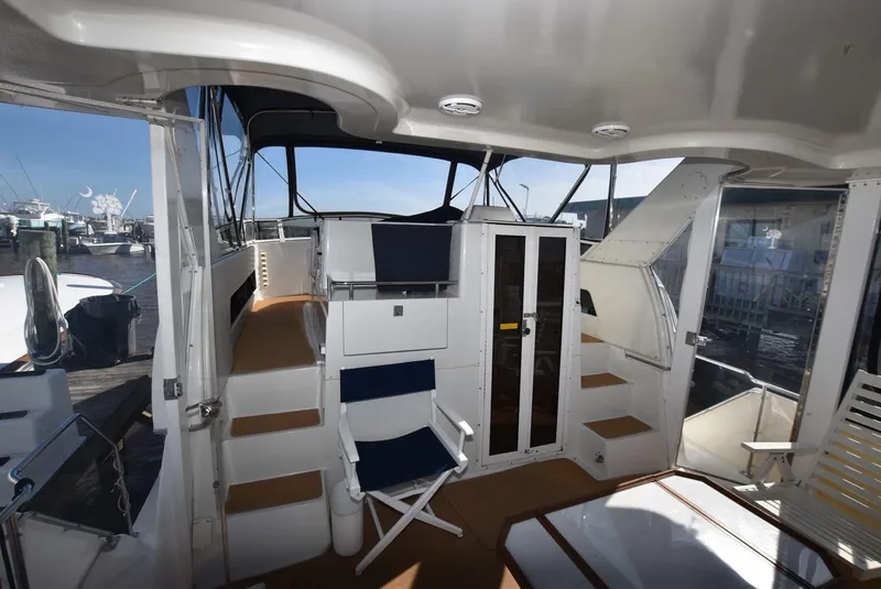 Slide: The Image of 1997 Carver 405 Aft Cabin Motoryacht interior with seating and stairs, docked at marina. - 7