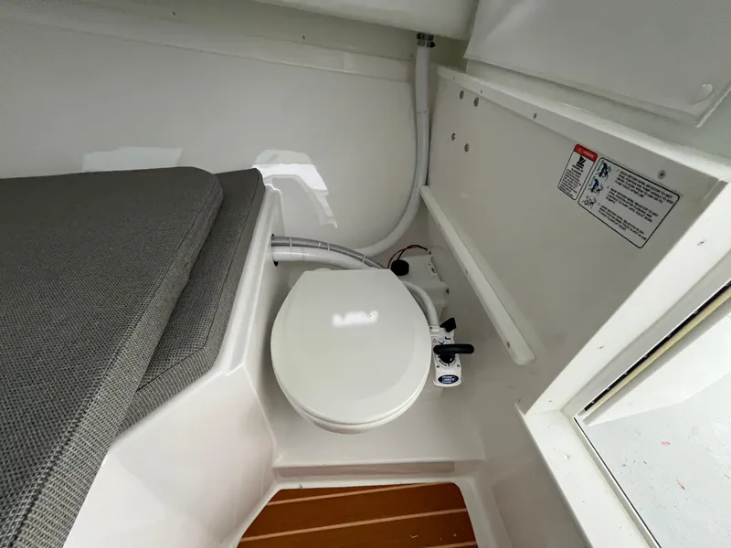 Slide: The Image of 2025 Steiger Craft 255 Miami boat interior with compact marine toilet and cushioned seating. - 11