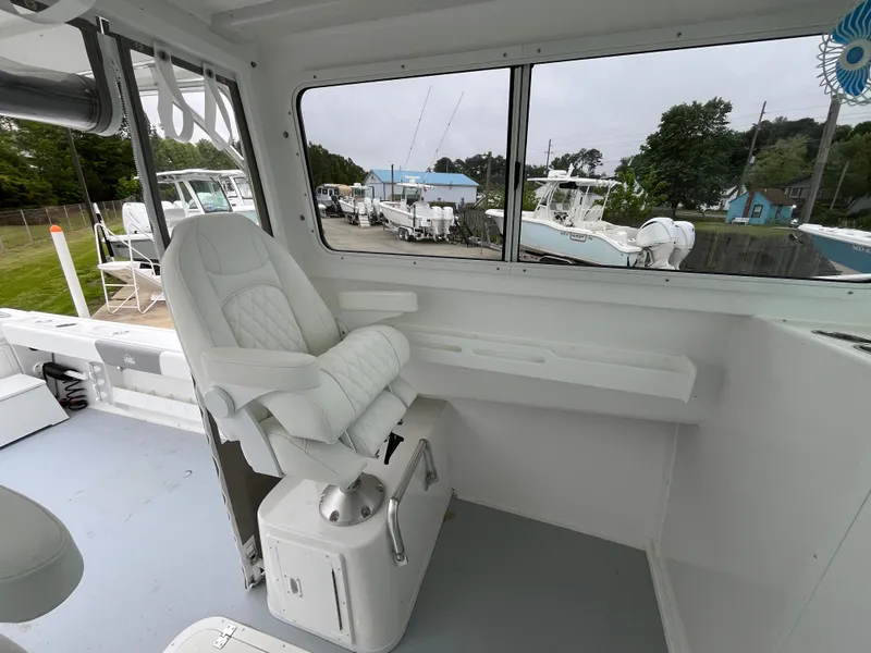 Slide: The Image of 2025 Steiger Craft 255 Miami boat interior with white captain's chair and window view. - 9