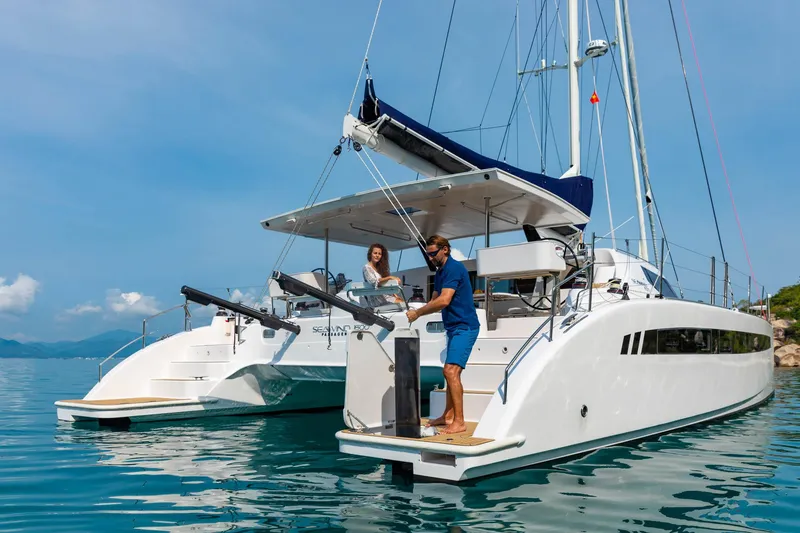 Slide: The Image of 2025 Seawind 1600 Passagemaker catamaran on calm water with two people on deck. - 23