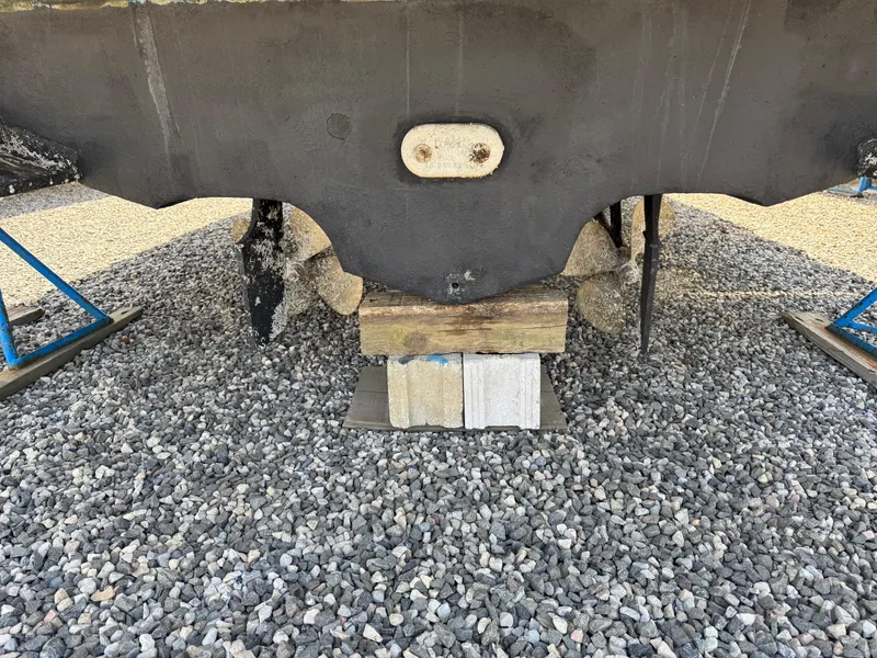 Slide: The Image of 1995 Sea Ray 400 Express Cruiser hull on gravel, supported by blocks and stands. - 11