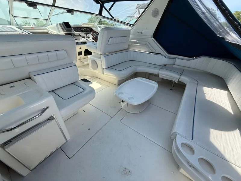 Slide: The Image of 1995 Sea Ray 400 Express Cruiser interior with white seating and helm, featuring a compact table. - 12