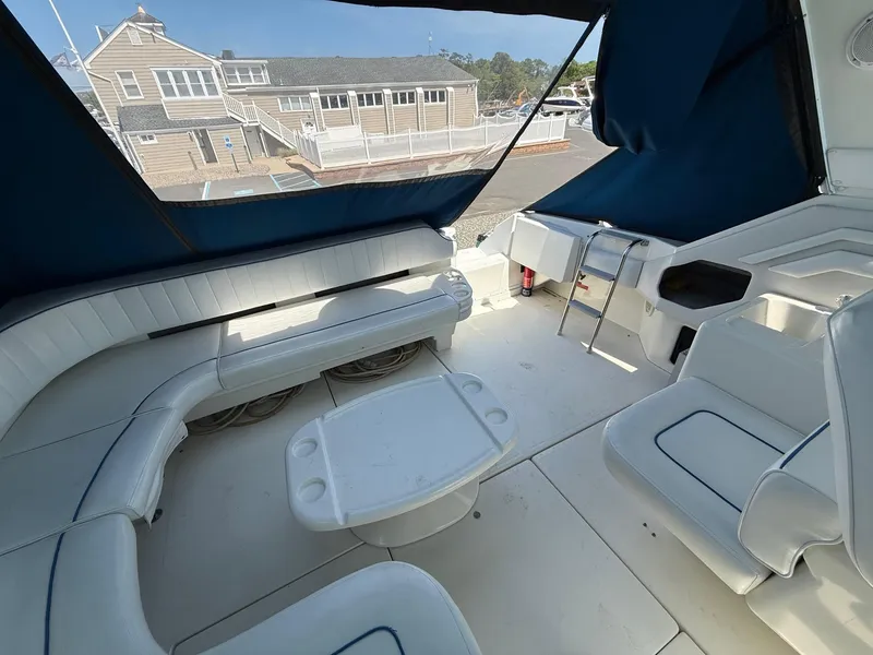 Slide: The Image of 1995 Sea Ray 400 Express Cruiser interior with white seating and table, docked near buildings. - 13