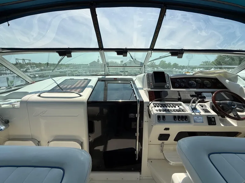 Slide: The Image of 1995 Sea Ray 400 Express Cruiser helm with controls and seating, overlooking marina. - 15