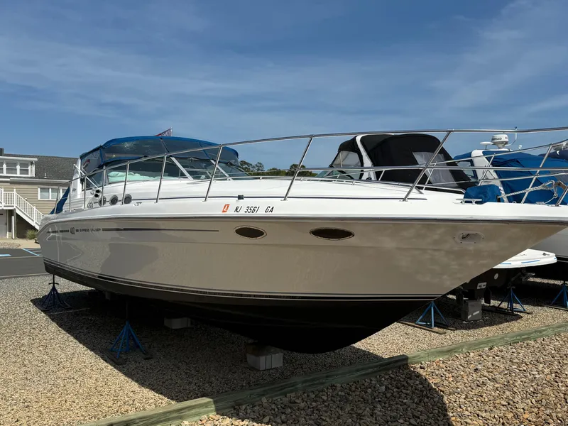 Slide: The Image of 1995 Sea Ray 400 Express Cruiser docked by waterfront homes, American flag visible. - 3