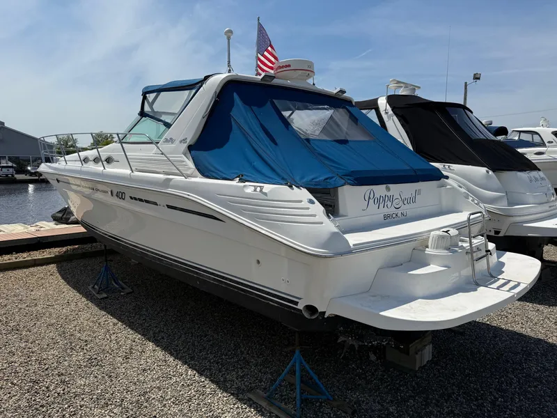 Slide: The Image of 1995 Sea Ray 400 Express Cruiser docked, featuring blue canopy and American flag. - 9