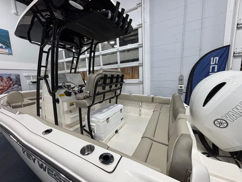 Slide: The Image of 2023 Key West 219 FS boat interior with seating, console, and Yamaha engine in showroom. - 17