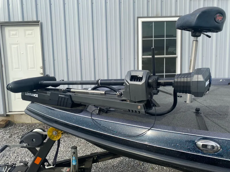 Slide: The Image of 2015 Ranger Z118 Comanche boat with Lowrance trolling motor, parked near a metal building. - 4