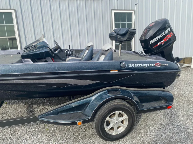 Slide: The Image of 2015 Ranger Z118 Comanche boat with Mercury engine, parked on gravel near a building. - 6