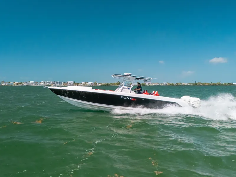 Slide: The Image of 2007 Donzi 38 ZF Cuddy boat cruising on open water under clear blue skies. - 32