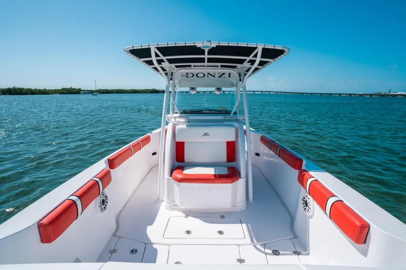 Slide: The Image of 2007 Donzi 38 ZF Cuddy boat with red seating, cruising on clear blue waters. - 6