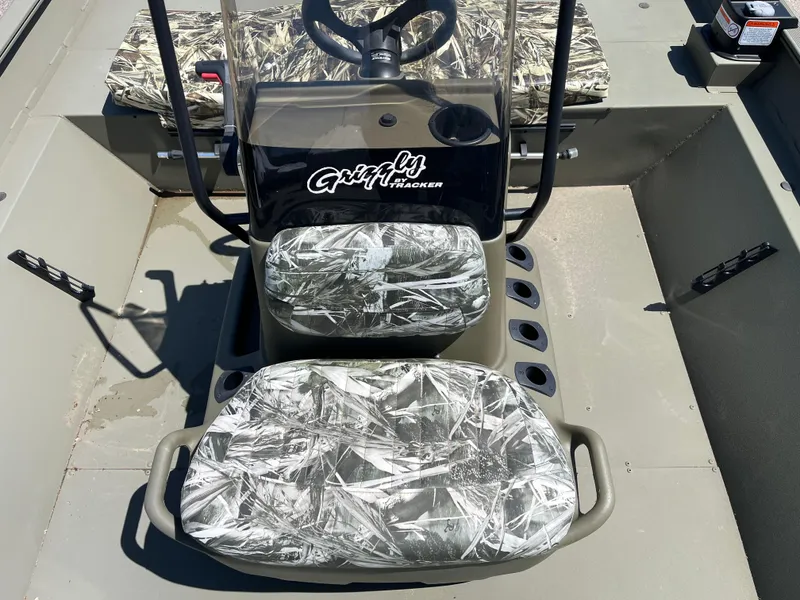 Slide: The Image of 2024 Tracker Grizzly 2072 CC boat interior with camo seats and steering console. - 5