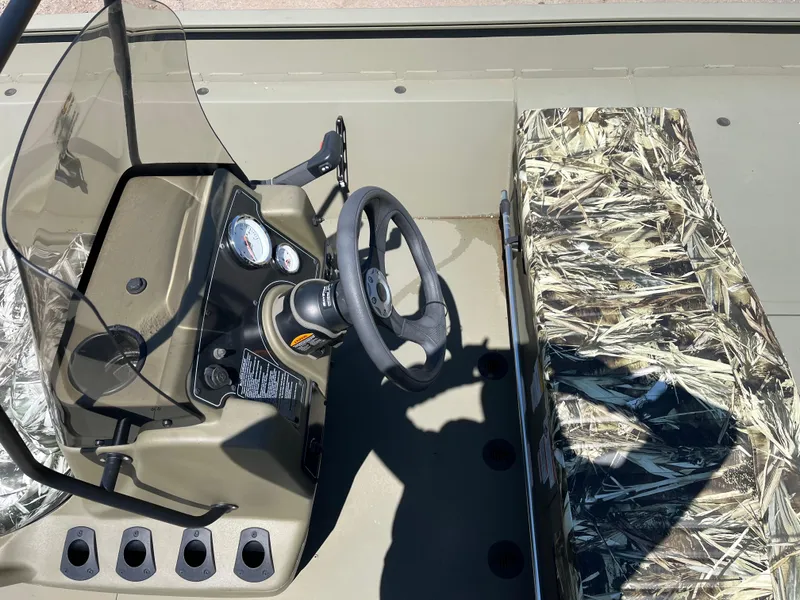 Slide: The Image of 2024 Tracker Grizzly 2072 CC boat interior with steering console and camo seating. - 7
