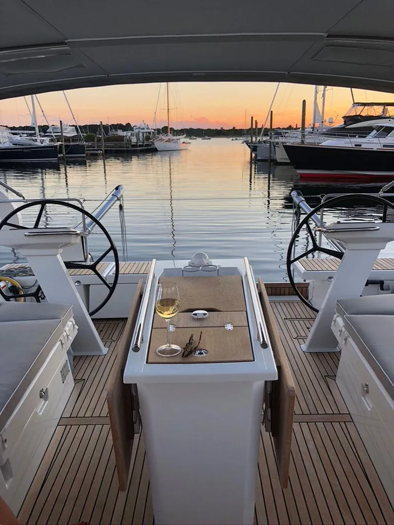 Slide: The Image of Beneteau Oceanis 51.1 yacht deck at sunset, featuring a table with wine. - 8