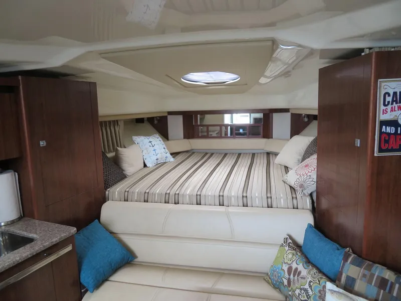 Slide: The Image of 2013 Monterey 340 Sport Yacht interior with cozy bed, cushions, and wooden cabinetry. - 12