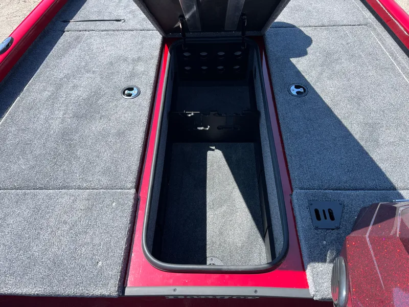 Slide: The Image of 2024 Ranger RT188 boat storage compartment with open lid, featuring gray carpet and red trim. - 8