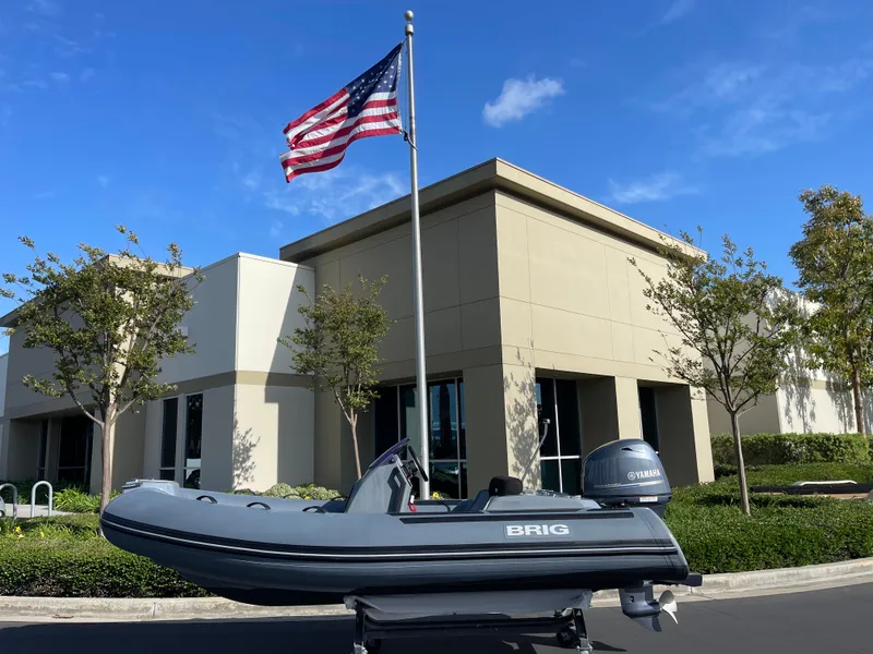 Slide: The Image of 2021 Brig Eagle 4 boat displayed outdoors with American flag and modern building backdrop. - 18