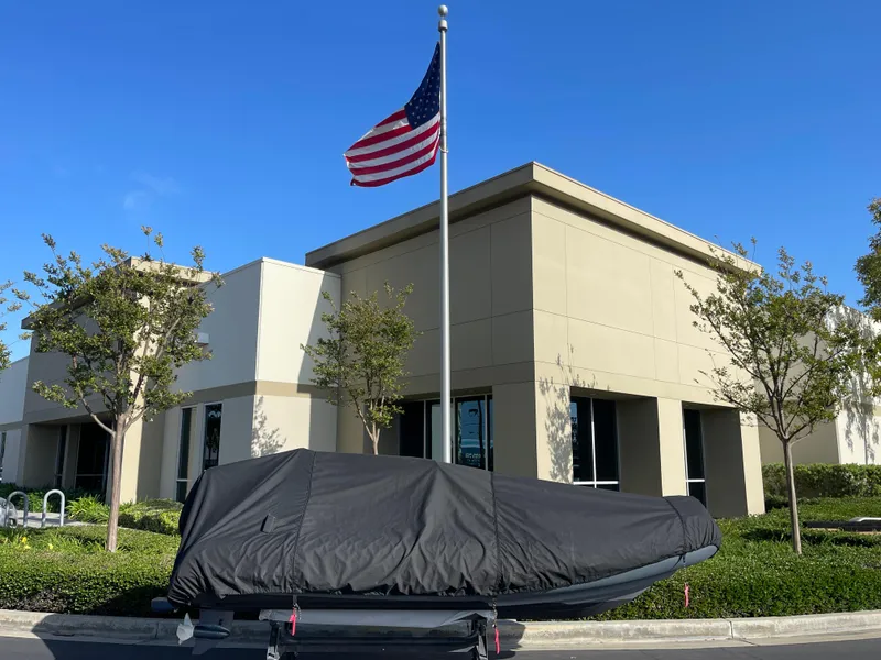 Slide: The Image of 2021 Brig Eagle 4 boat covered, parked near a building with an American flag. - 33