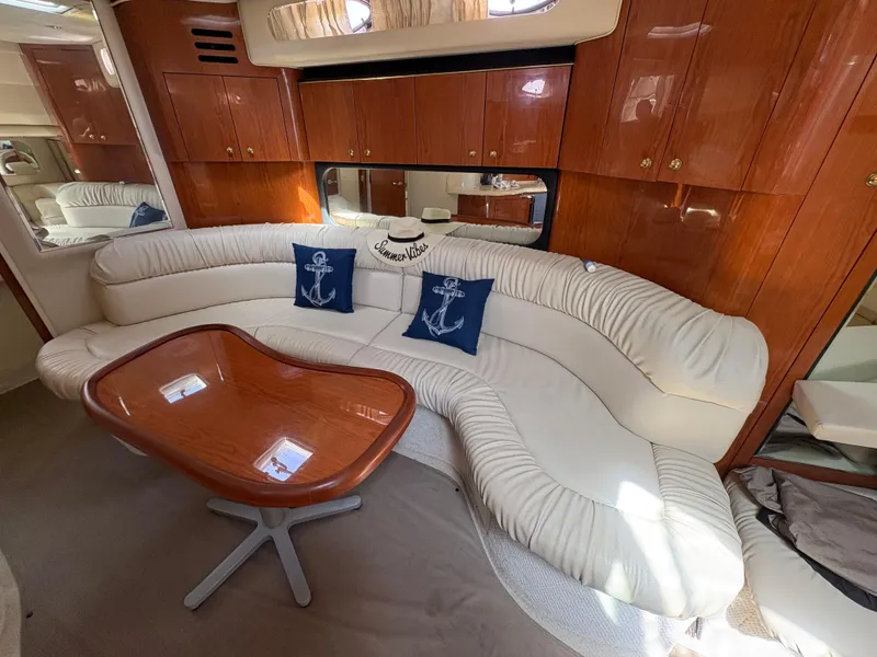 Slide: The Image of Interior of 1999 Sea Ray 380 Sundancer with white leather seating and wooden table. - 10