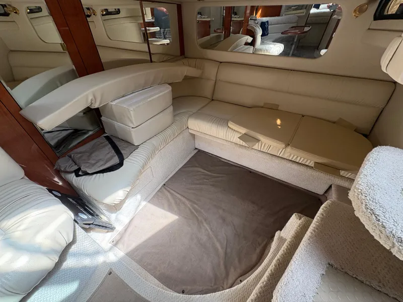 Slide: The Image of 1999 Sea Ray 380 Sundancer interior with beige seating and carpeted flooring. - 9