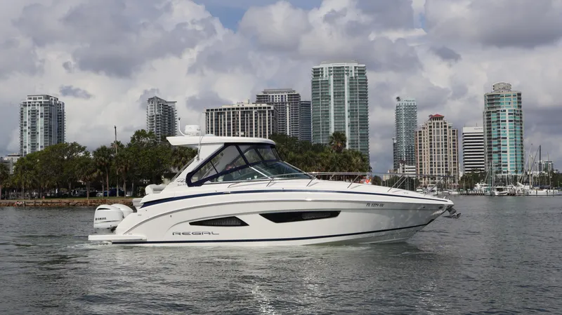 Slide: The Image of 2021 Regal 33 XO boat cruising near city skyline with cloudy sky. - 10