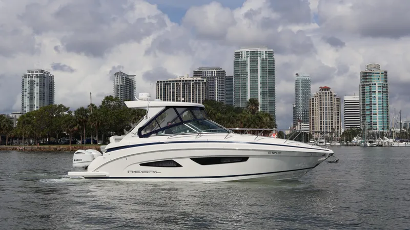 Slide: The Image of 2021 Regal 33 XO boat cruising near city skyline on a cloudy day. - 12