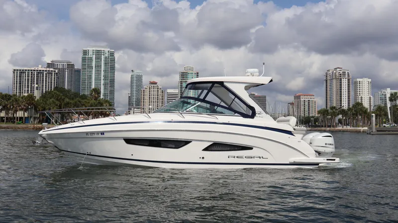 Slide: The Image of 2021 Regal 33 XO boat cruising near city skyline under cloudy skies. - 5