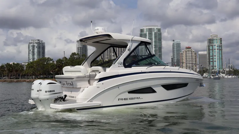 Slide: The Image of 2021 Regal 33 XO boat cruising near city skyline, featuring sleek design and Yamaha engines. - 6