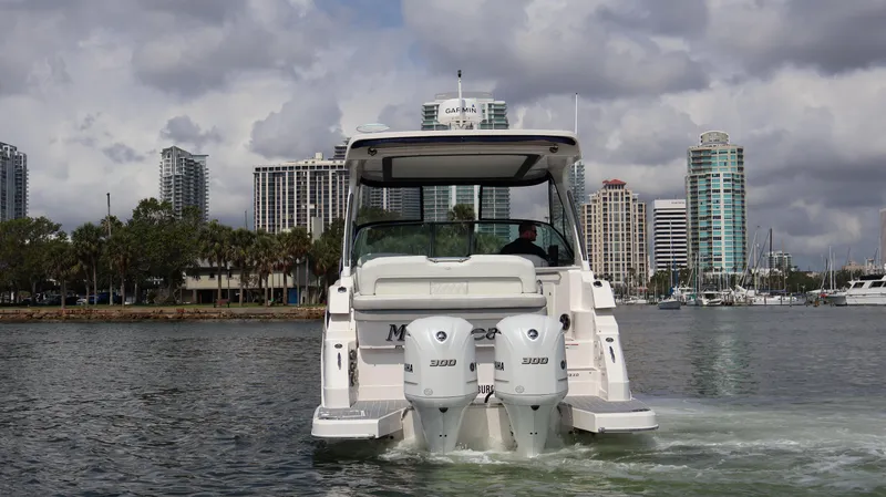 Slide: The Image of 2021 Regal 33 XO boat cruising near city skyline under cloudy skies. - 7