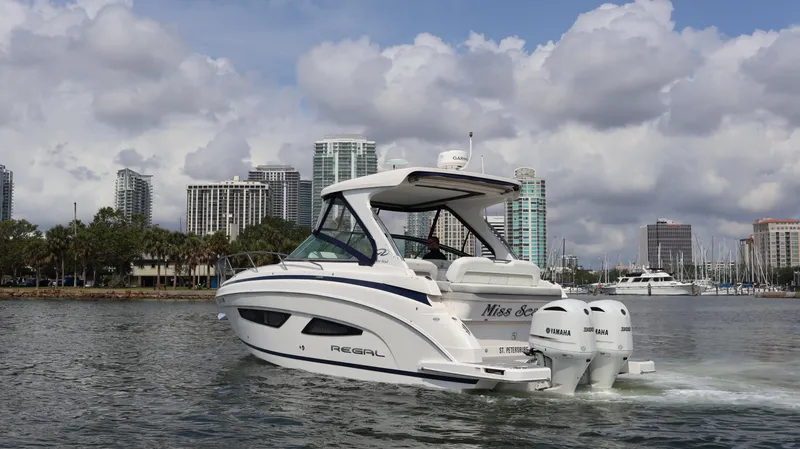 Slide: The Image of 2021 Regal 33 XO boat cruising near city skyline under cloudy sky. - 8