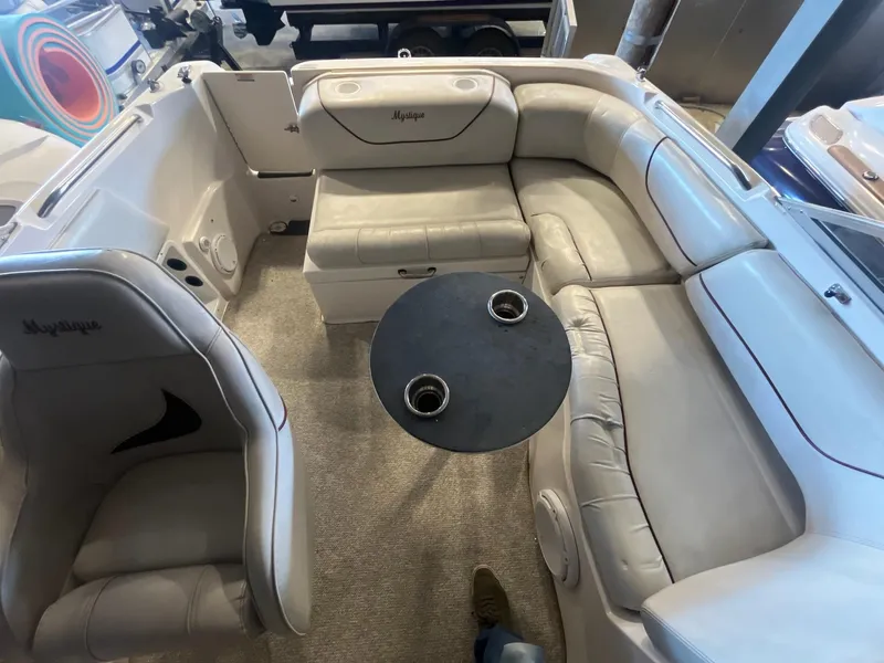 Slide: The Image of Interior of a 2002 Ebbtide 2400 Mystique boat with beige seating and a round table. - 19