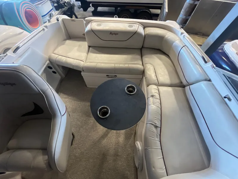 Slide: The Image of 2002 Ebbtide 2400 Mystique boat interior with beige seating and round table. - 20