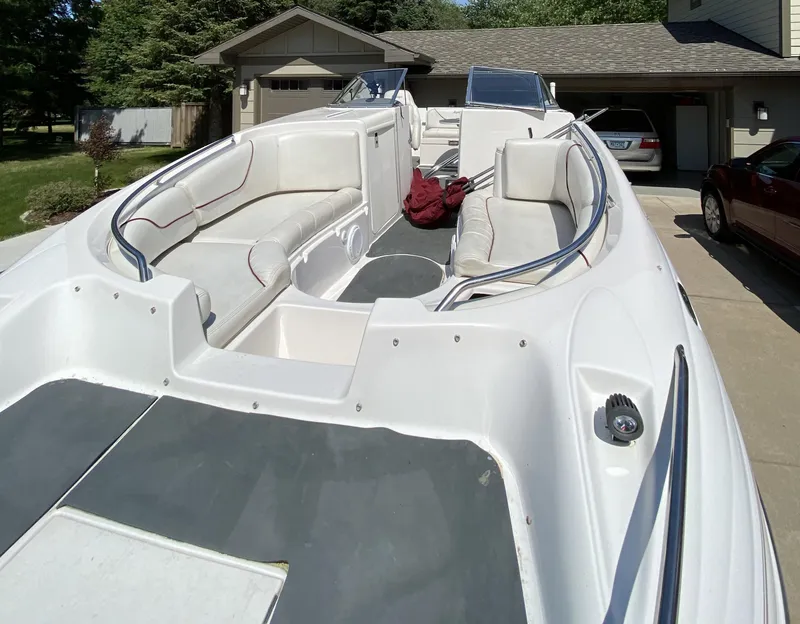 Slide: The Image of 2002 Ebbtide 2400 Mystique boat with spacious seating, parked in a driveway. - 3