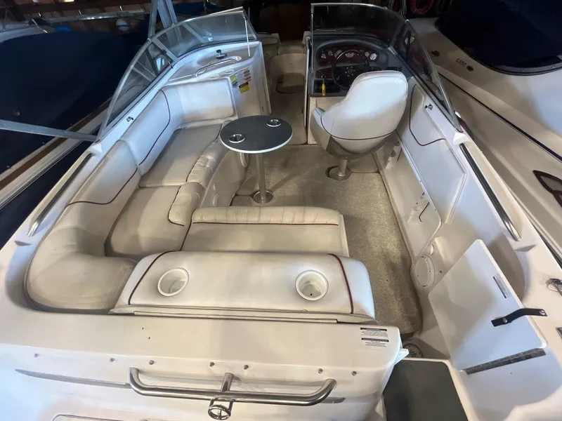 Slide: The Image of 2002 Ebbtide 2400 Mystique boat interior with white seating and small table. - 4