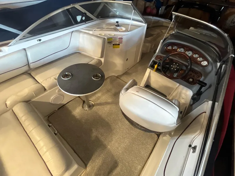 Slide: The Image of 2002 Ebbtide 2400 Mystique boat interior with seating, table, and dashboard. - 5