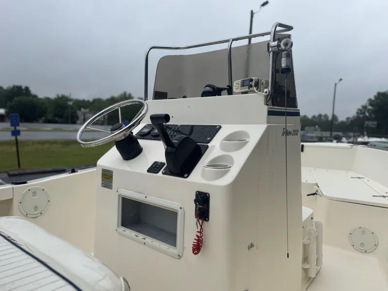 Slide: The Image of 2003 Sea Hunt 202 TRITON boat console with steering wheel and controls, docked outdoors. - 6