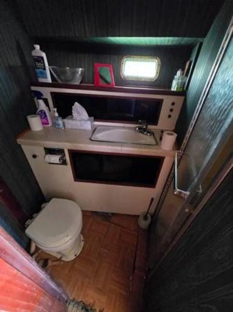 Slide: The Image of 1979 Viking Yacht bathroom with sink, toilet, and small window. - 12