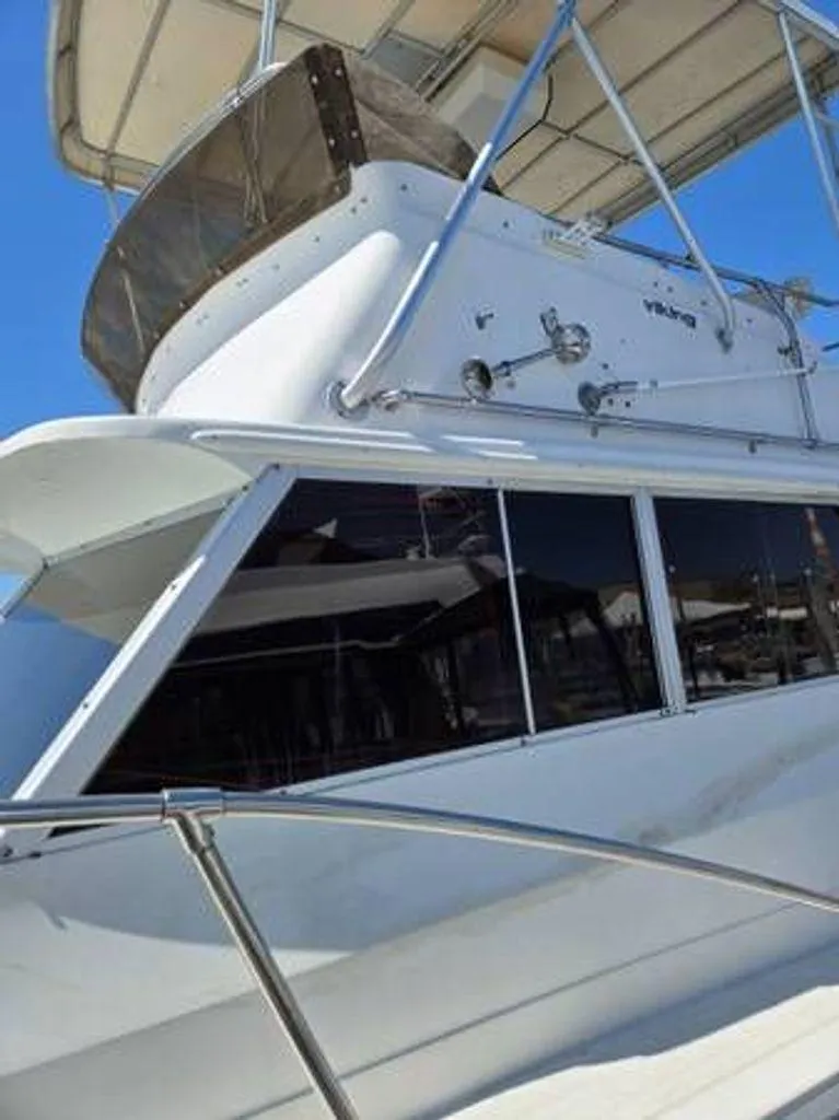 Slide: The Image of 1979 Viking Yacht with flybridge, white exterior, and sleek design under a clear blue sky. - 3