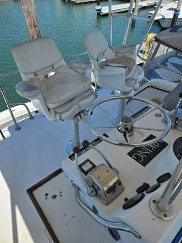 Slide: The Image of 1979 Viking Yacht helm with dual captain chairs and steering wheel, docked at marina. - 6
