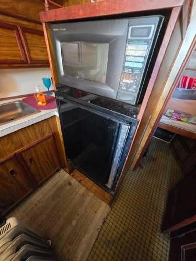 Slide: The Image of 1979 Viking Yacht kitchen with microwave, fridge, and wooden cabinetry. - 9
